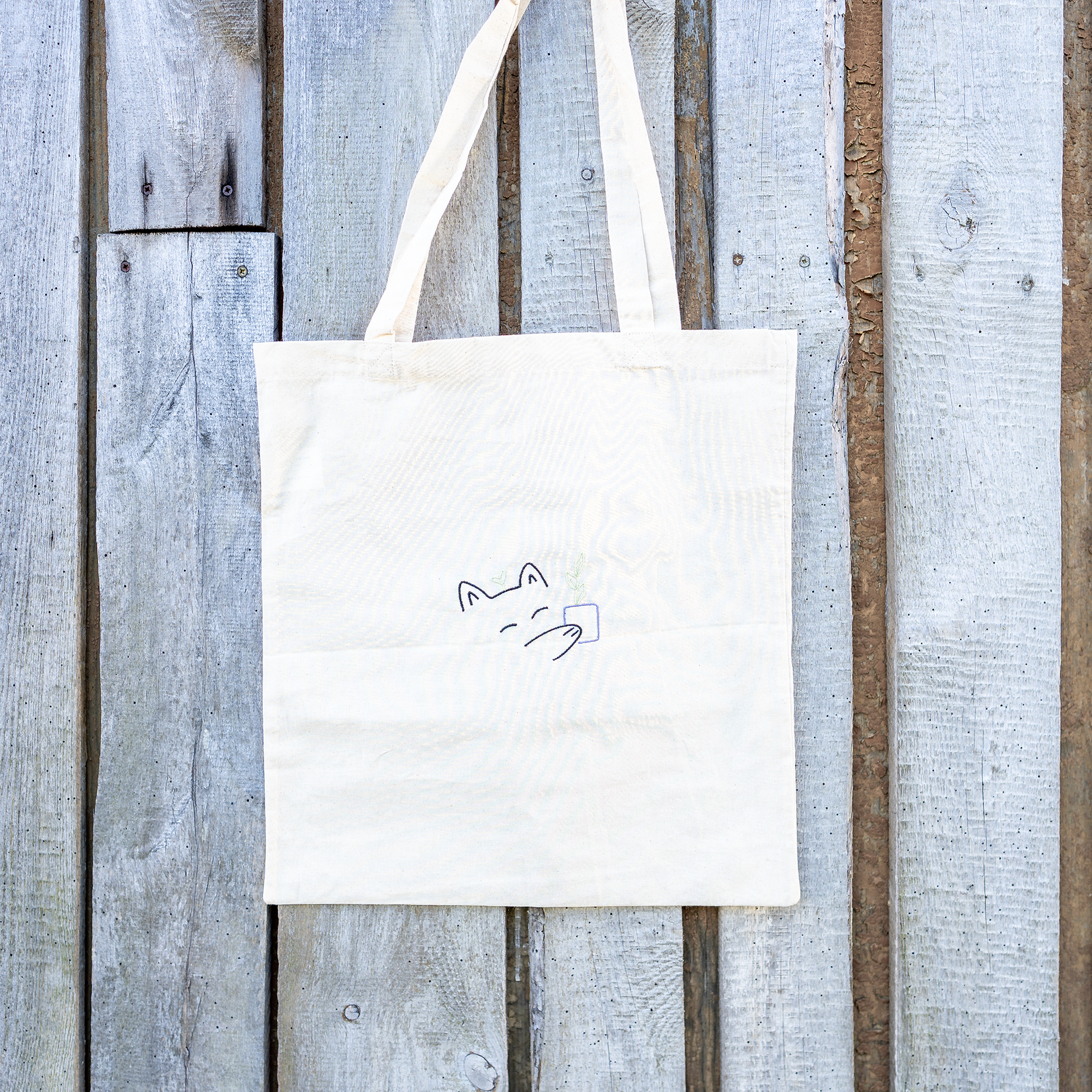 Nachhaltige Baumwoll-Tragetasche mit verspieltem Katzenmotiv und Pflanze in der Pfote