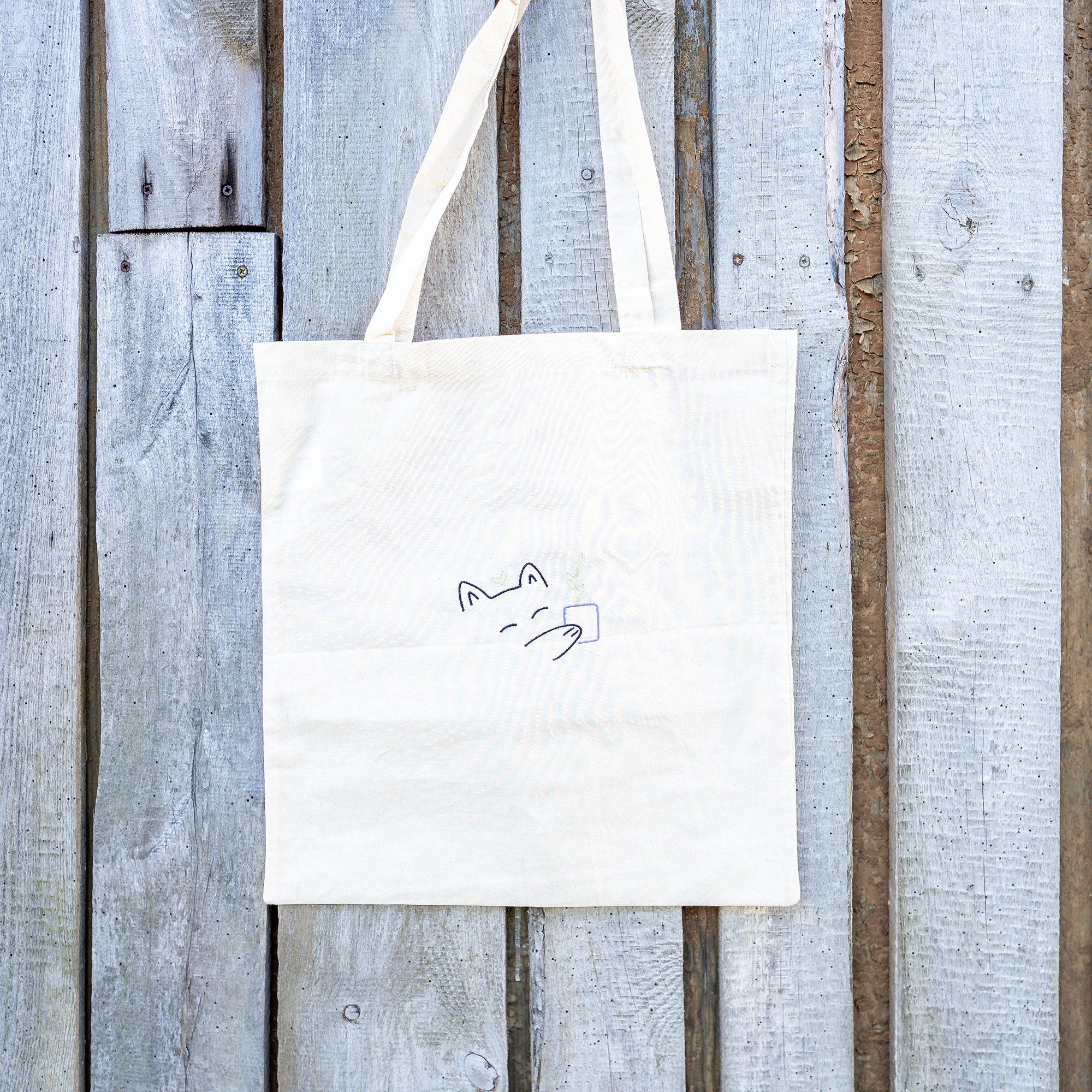 Nachhaltige Baumwoll-Tragetasche mit verspieltem Katzenmotiv und Pflanze in der Pfote